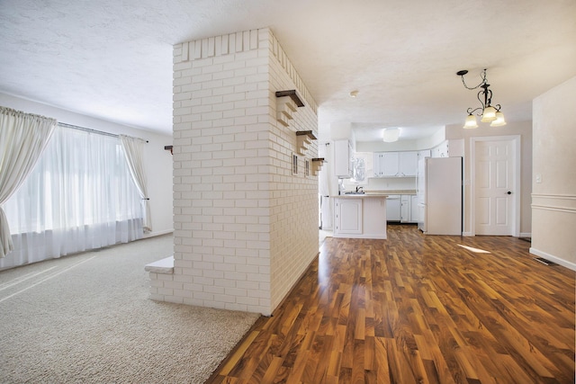 interior space featuring a textured ceiling, brick wall, and dark hardwood / wood-style flooring