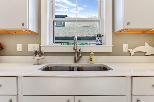 kitchen featuring light stone countertops, sink, and white cabinets
