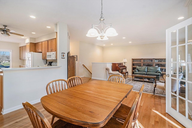 dining space featuring ceiling fan with notable chandelier and light hardwood / wood-style floors