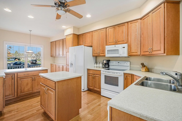 kitchen featuring a kitchen island, sink, hanging light fixtures, light hardwood / wood-style floors, and white appliances