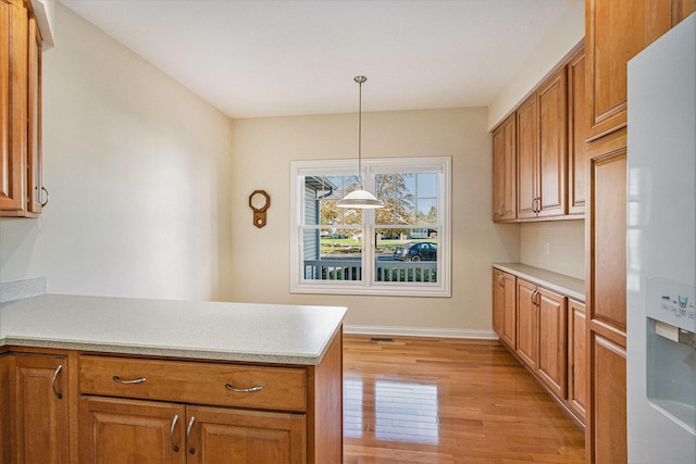 kitchen with white refrigerator with ice dispenser, pendant lighting, and light hardwood / wood-style floors