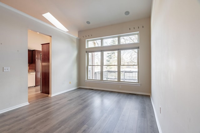 unfurnished room featuring a skylight and light hardwood / wood-style floors