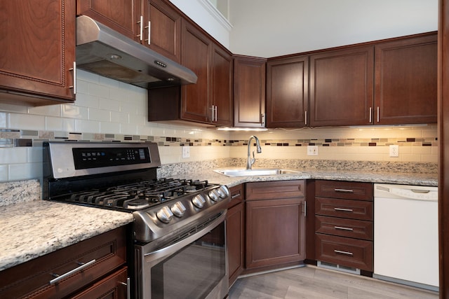 kitchen with white dishwasher, sink, stainless steel range with gas stovetop, backsplash, and light stone counters