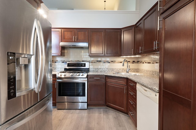 kitchen with light stone countertops, stainless steel appliances, sink, ornamental molding, and light wood-type flooring