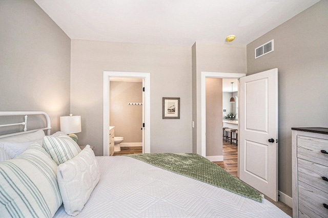 bedroom with hardwood / wood-style floors and ensuite bathroom