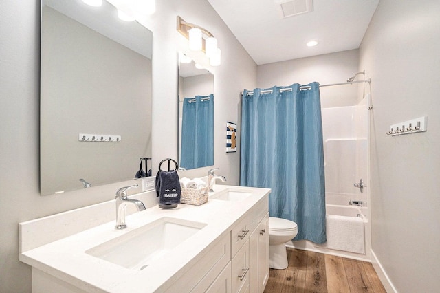 full bathroom featuring vanity, hardwood / wood-style flooring, shower / bath combination with curtain, and toilet