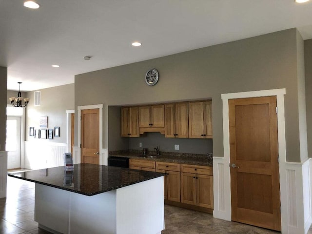 kitchen featuring pendant lighting, a kitchen island, black dishwasher, sink, and a notable chandelier