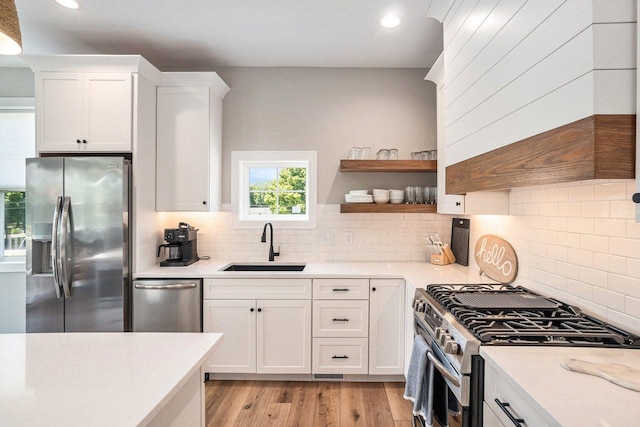 kitchen with light hardwood / wood-style flooring, sink, backsplash, white cabinets, and stainless steel appliances