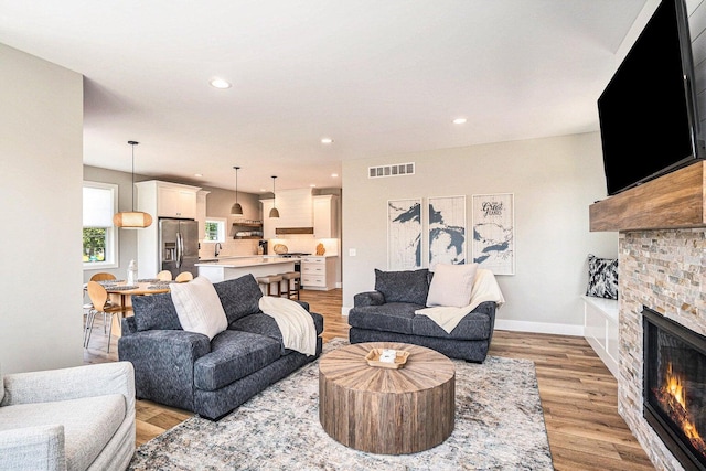 living room with light hardwood / wood-style floors and a stone fireplace