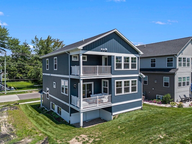 rear view of house featuring a balcony and a lawn