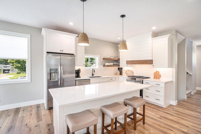 kitchen featuring pendant lighting, light hardwood / wood-style flooring, sink, white cabinets, and stainless steel appliances