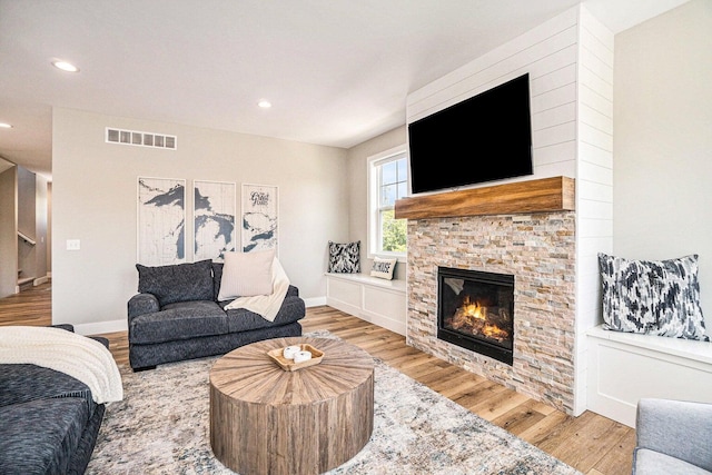 living room featuring light wood-type flooring and a stone fireplace