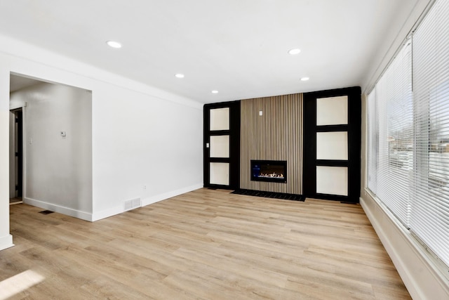 unfurnished living room with light wood-type flooring and a large fireplace