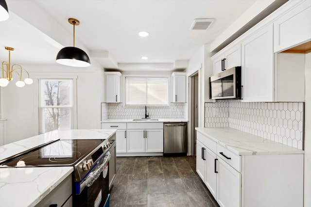 kitchen featuring appliances with stainless steel finishes, white cabinetry, sink, pendant lighting, and light stone counters