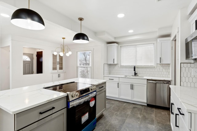 kitchen featuring stainless steel appliances, white cabinetry, hanging light fixtures, and light stone counters