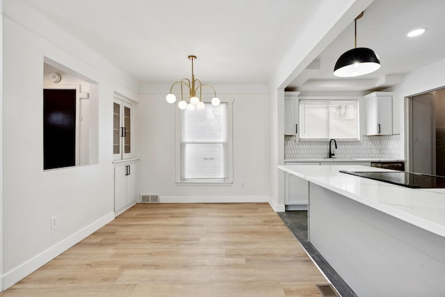 kitchen featuring light stone countertops, pendant lighting, white cabinets, and tasteful backsplash