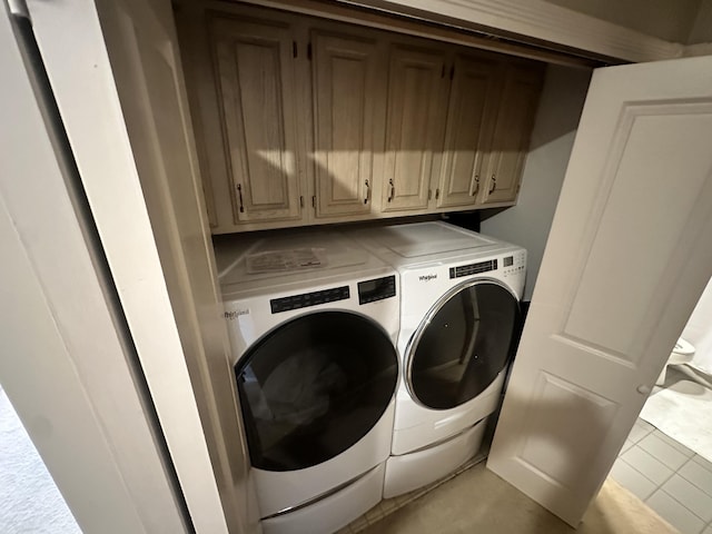 clothes washing area featuring light tile patterned floors, cabinets, and washer and clothes dryer