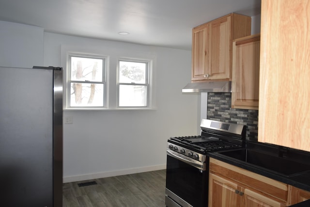 kitchen featuring dark hardwood / wood-style floors, stainless steel gas range, light brown cabinetry, and decorative backsplash