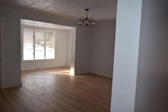 empty room featuring ornamental molding, a chandelier, and hardwood / wood-style floors