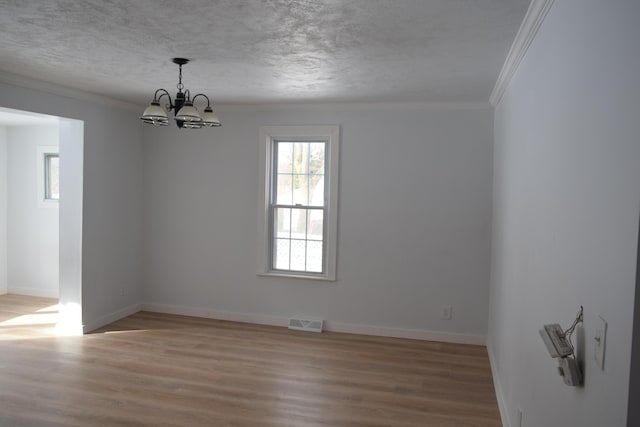 empty room featuring crown molding, a chandelier, a textured ceiling, and light wood-type flooring