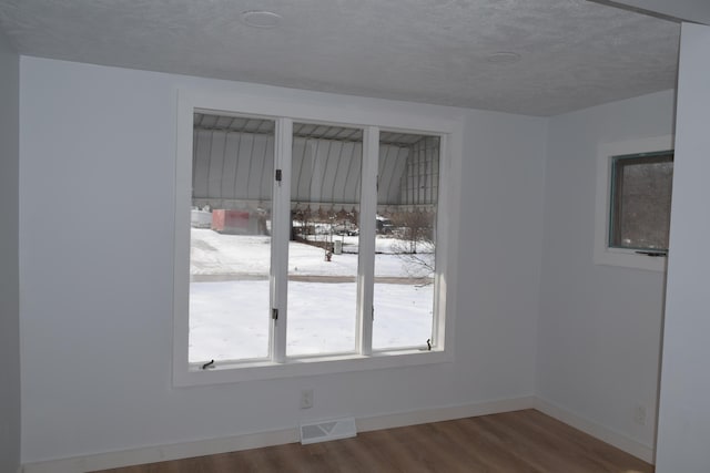 unfurnished room with wood-type flooring and a textured ceiling