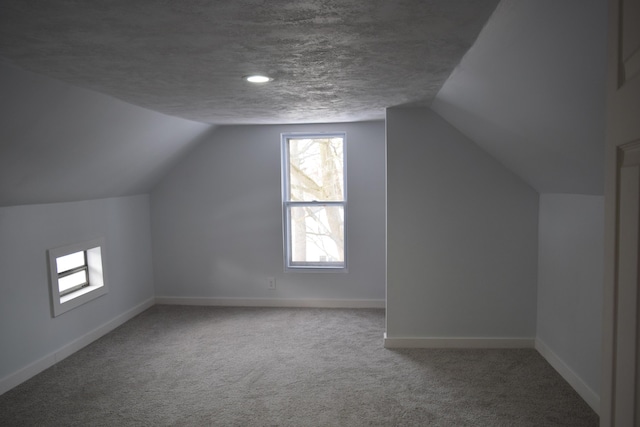 bonus room with lofted ceiling, carpet floors, and a textured ceiling