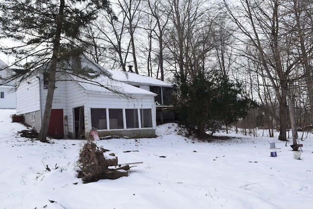 view of snowy exterior featuring a sunroom