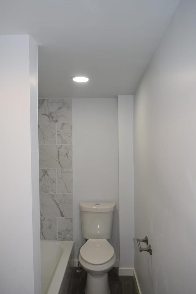 bathroom with toilet, a bathing tub, and hardwood / wood-style floors