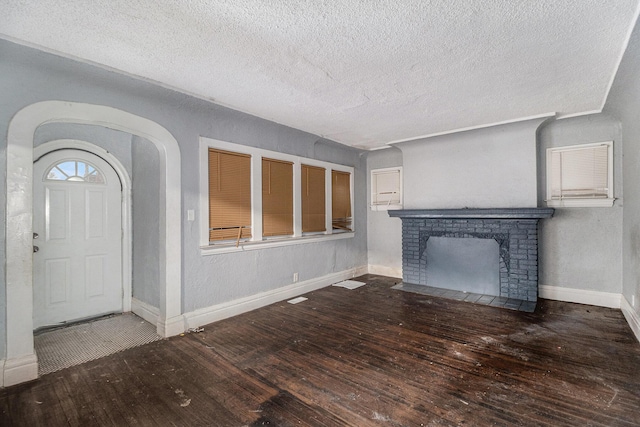 unfurnished living room featuring hardwood / wood-style flooring, a brick fireplace, and a textured ceiling