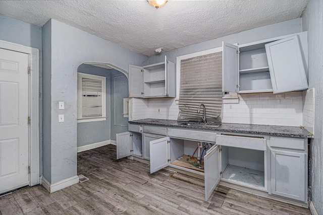 kitchen with white cabinetry, wood-type flooring, sink, decorative backsplash, and a textured ceiling