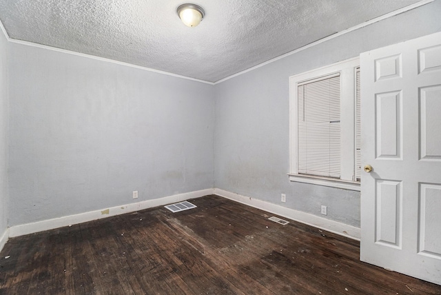 spare room featuring ornamental molding, dark hardwood / wood-style floors, and a textured ceiling