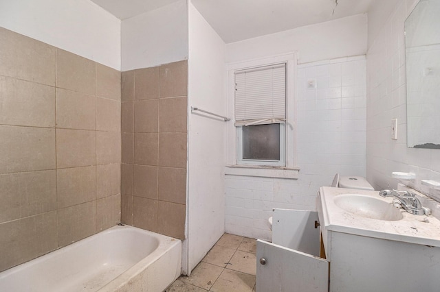 bathroom with a tub to relax in, tile patterned flooring, vanity, and tile walls