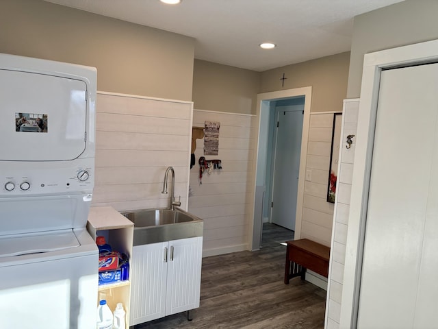 washroom featuring dark wood-style flooring, stacked washer / drying machine, recessed lighting, a sink, and laundry area