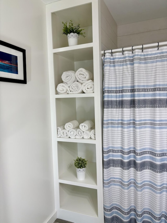 full bathroom with curtained shower and built in shelves