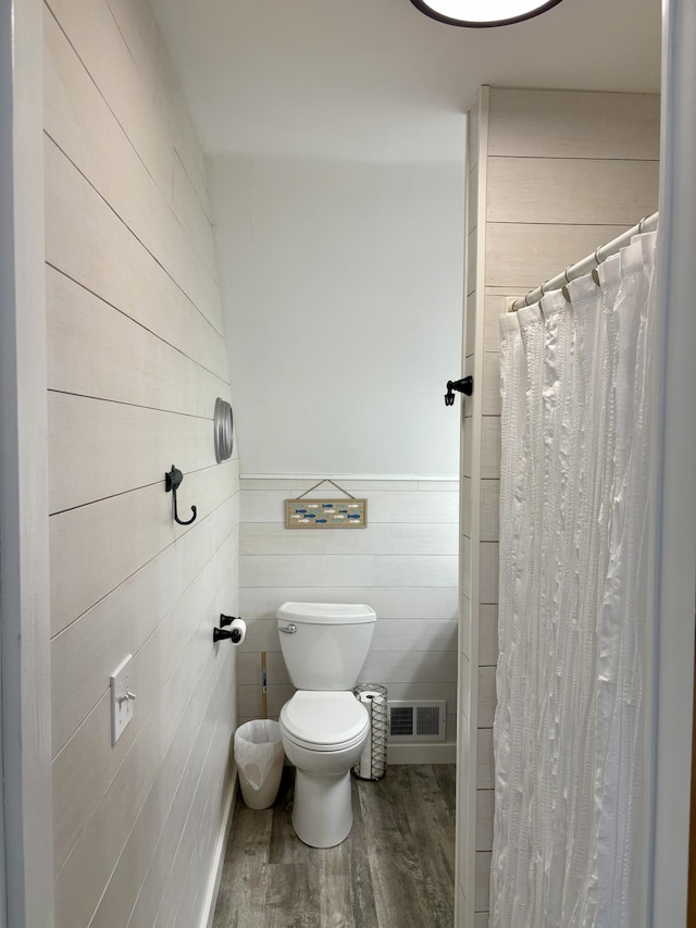 bathroom featuring visible vents, toilet, wainscoting, wood finished floors, and a shower with curtain