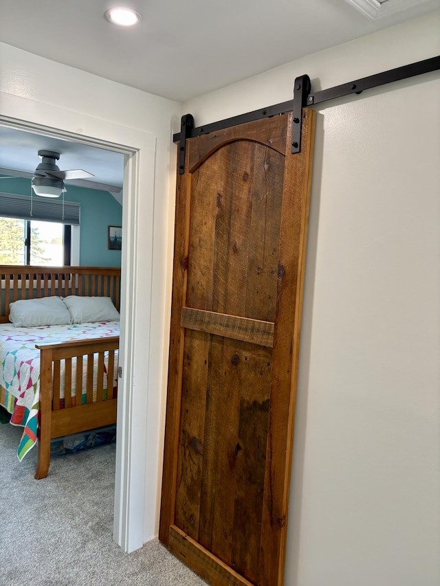 unfurnished bedroom with a barn door and carpet