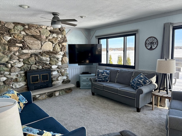 carpeted living area featuring plenty of natural light, a fireplace, ceiling fan, and a textured ceiling