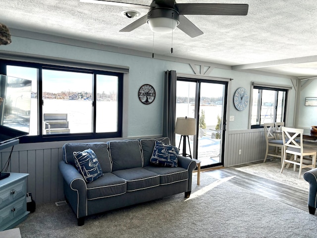 living area with a wainscoted wall, ceiling fan, a textured ceiling, and wood finished floors