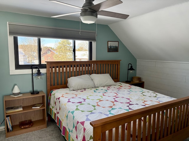 bedroom with a ceiling fan, lofted ceiling, carpet flooring, and wooden walls