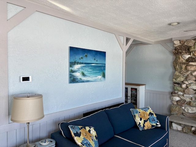 carpeted living room with a wainscoted wall, a textured wall, and a textured ceiling