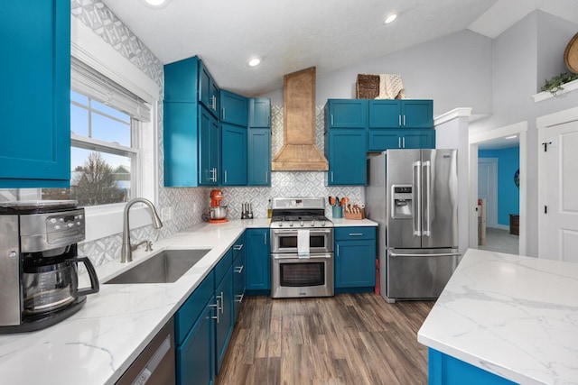 kitchen with stainless steel appliances, sink, vaulted ceiling, light stone counters, and custom range hood