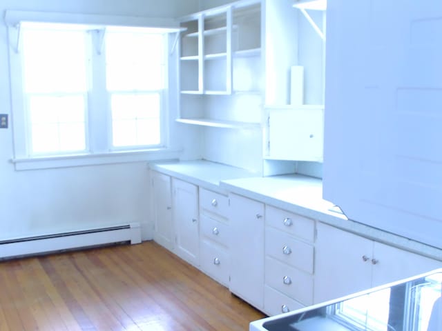 kitchen featuring white cabinetry, baseboard heating, and light wood-type flooring