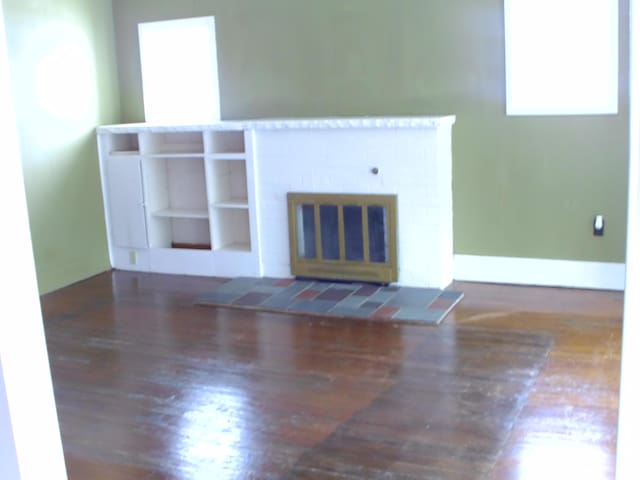 unfurnished living room featuring dark wood-type flooring, plenty of natural light, and a fireplace