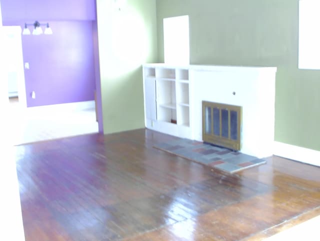 unfurnished living room with dark wood-type flooring and a tile fireplace