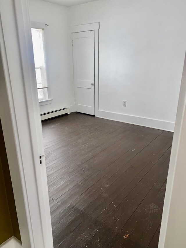 empty room with a baseboard radiator and dark hardwood / wood-style flooring