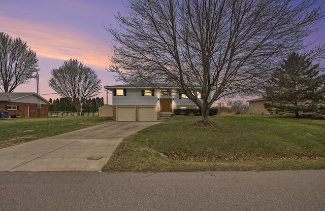 raised ranch featuring a garage and a lawn