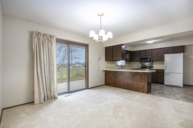 kitchen featuring kitchen peninsula, dark brown cabinets, pendant lighting, appliances with stainless steel finishes, and sink