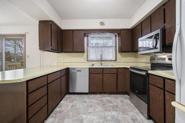 kitchen featuring sink, kitchen peninsula, stainless steel appliances, and dark brown cabinets