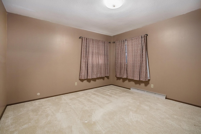 spare room featuring carpet, a textured ceiling, and a baseboard heating unit