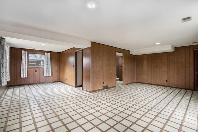 unfurnished living room featuring wood walls